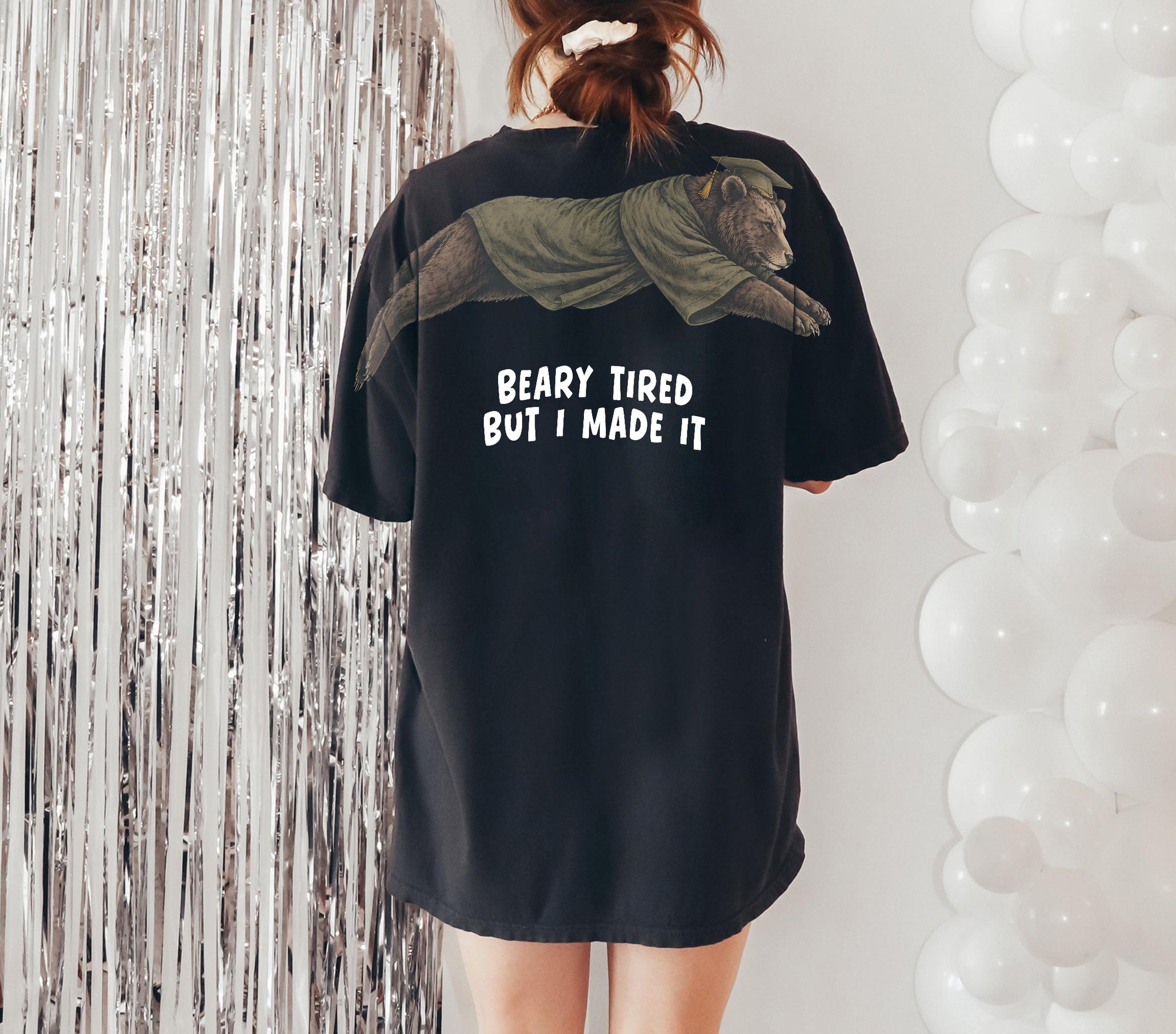 Bear Beary Tired But I Made It graduation graphic tee by Dripvity, unisex oversized white t-shirt with leaping bear in graduation cap and gown