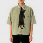 Novelty necktie featuring a realistic black cat appearing to hang from the wearer's collar