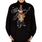 Novelty necktie featuring a tabby cat dressed as a cowboy, wearing a yellow plaid shirt, leopard print vest, jeans, bandana, and looking up at a dangling cowboy hat