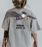 Eagle Soaring Outta 26 graduation graphic tee by Dripvity, unisex oversized white t-shirt with flying bald eagle in graduation cap and diploma