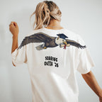 Eagle Soaring Outta 26 graduation graphic tee by Dripvity, unisex oversized white t-shirt with flying bald eagle in graduation cap and diploma