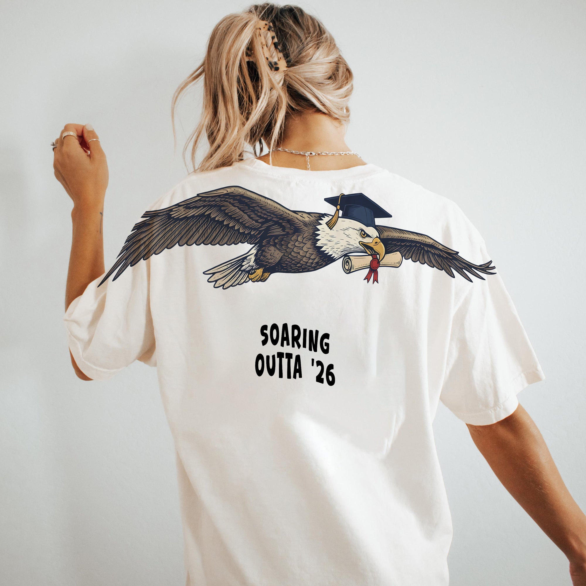 Eagle Soaring Outta 26 graduation graphic tee by Dripvity, unisex oversized white t-shirt with flying bald eagle in graduation cap and diploma