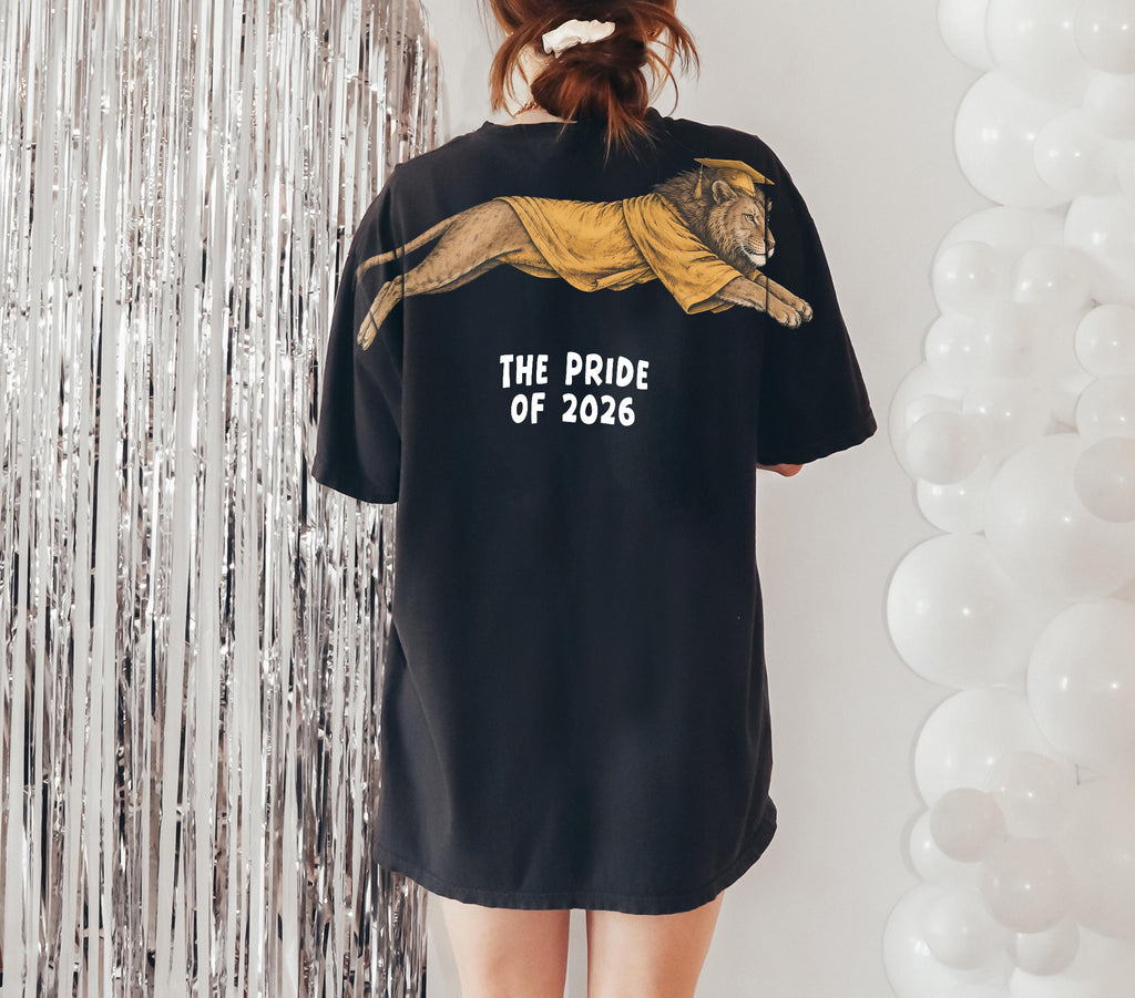 Lion The Pride of 2026 graduation graphic tee by Dripvity, unisex oversized white t-shirt with leaping lion in graduation cap and gown