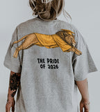 Lion The Pride of 2026 graduation graphic tee by Dripvity, unisex oversized white t-shirt with leaping lion in graduation cap and gown