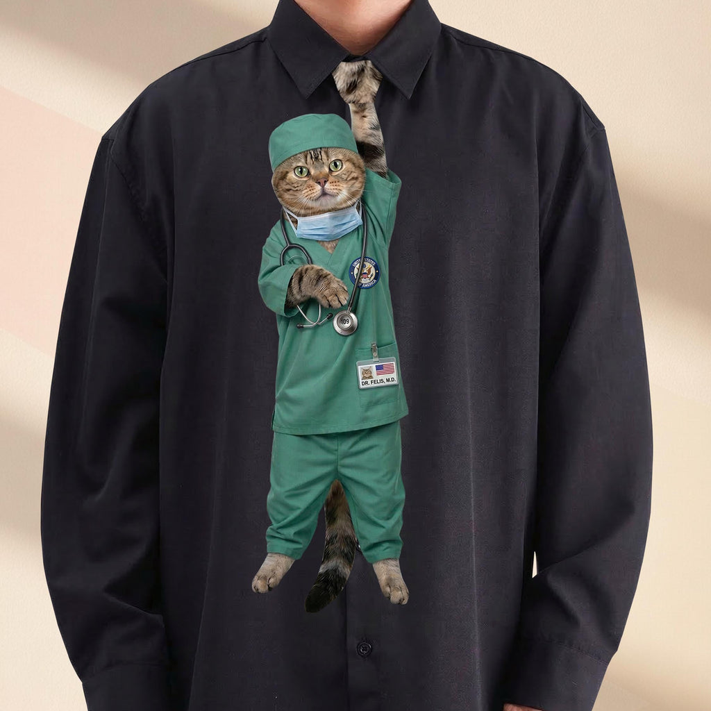 Novelty necktie featuring a tabby cat dressed in green medical scrubs, a surgical cap, and a face mask, with a stethoscope draped around its neck and a US flag name tag