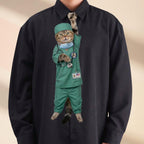 Novelty necktie featuring a tabby cat dressed in green medical scrubs, a surgical cap, and a face mask, with a stethoscope draped around its neck and a US flag name tag