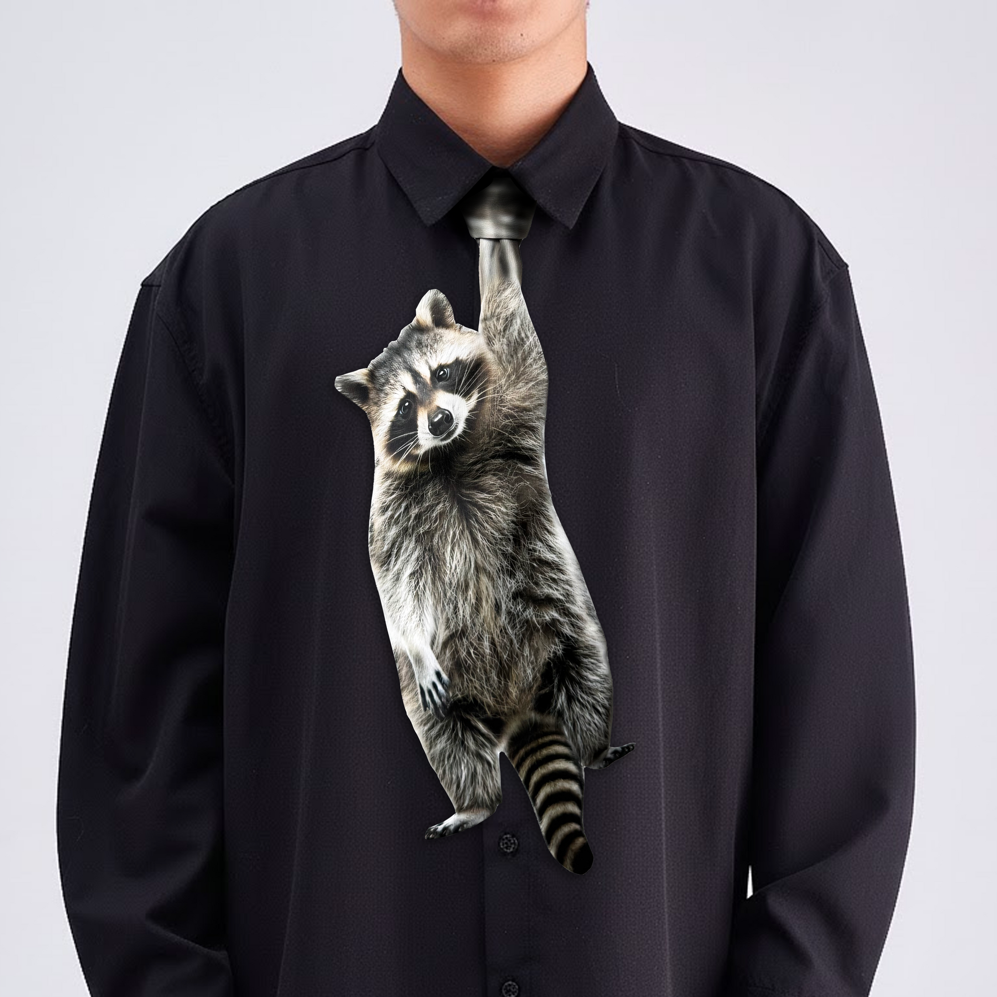 Novelty necktie featuring a realistic hanging raccoon design, a fun and unique fashion accessory.