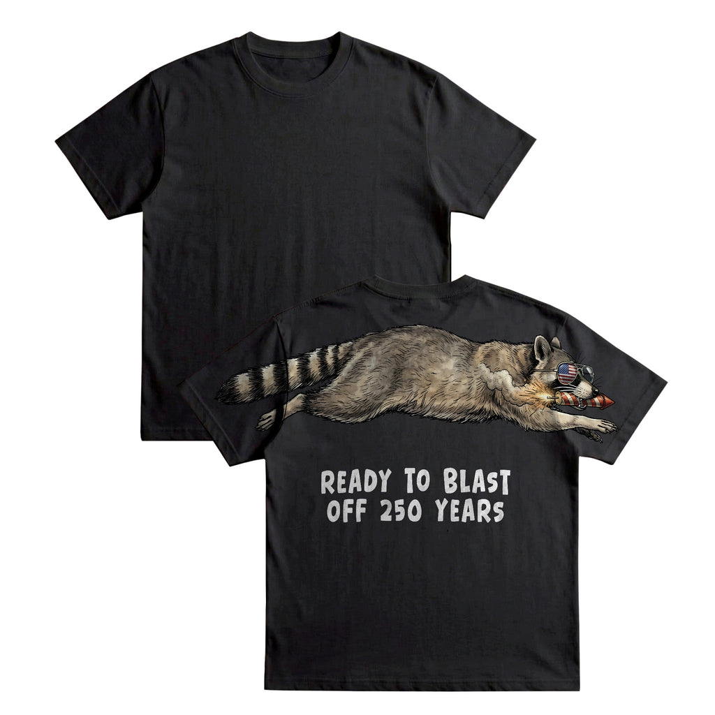 Raccoon ready to blast off 250 years graphic tee by Dripvity, unisex oversized black t-shirt with patriotic raccoon and fireworks design