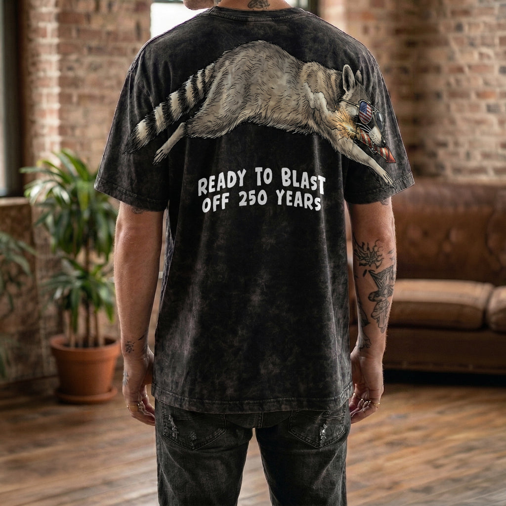 Raccoon ready to blast off 250 years graphic tee by Dripvity, unisex oversized black t-shirt with patriotic raccoon and fireworks design
