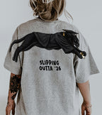 Slipping Outta 26 Panther Graduation Graphic Tee By Dripvity. Edgy unisex oversized black washed t-shirt with leaping panther in graduation cap. Perfect 2026 senior graduation streetwear gift. Shop now!