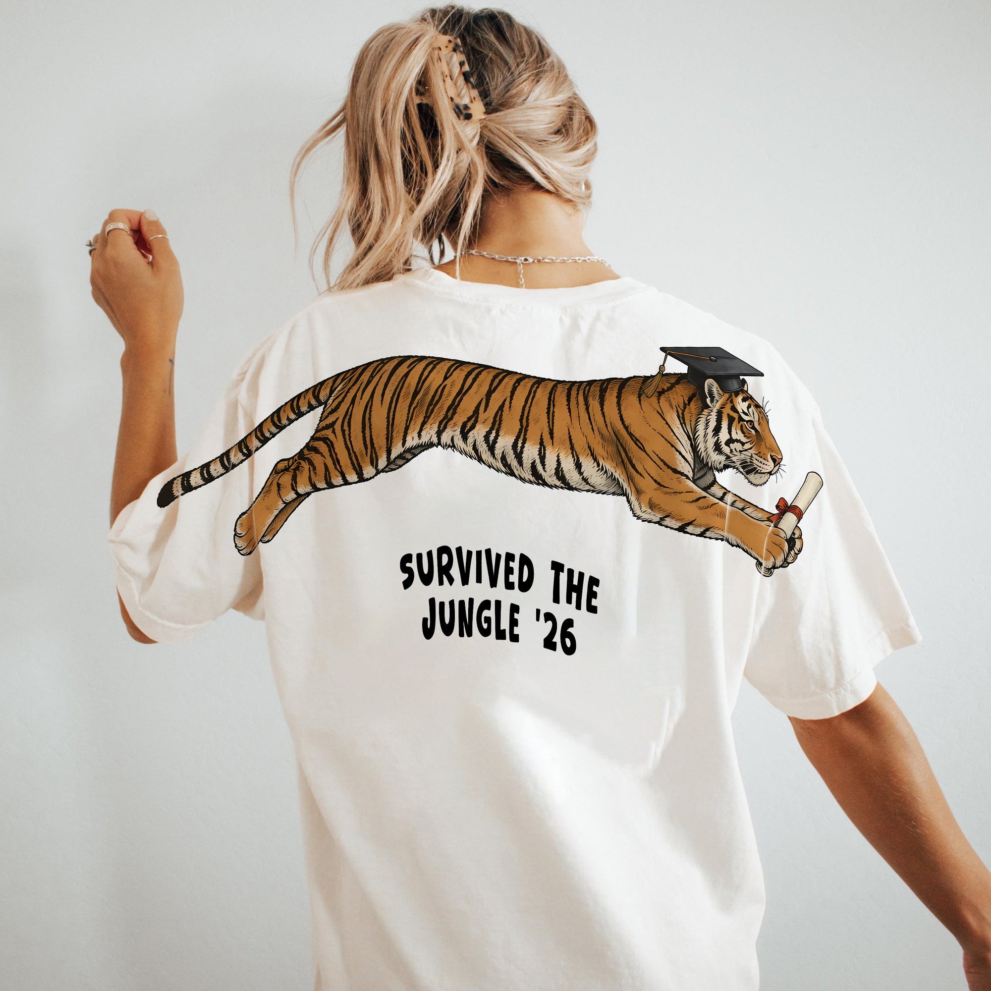 Tiger Survived The Jungle 26 graduation graphic tee by Dripvity, unisex oversized white t-shirt with leaping tiger in graduation cap and diploma