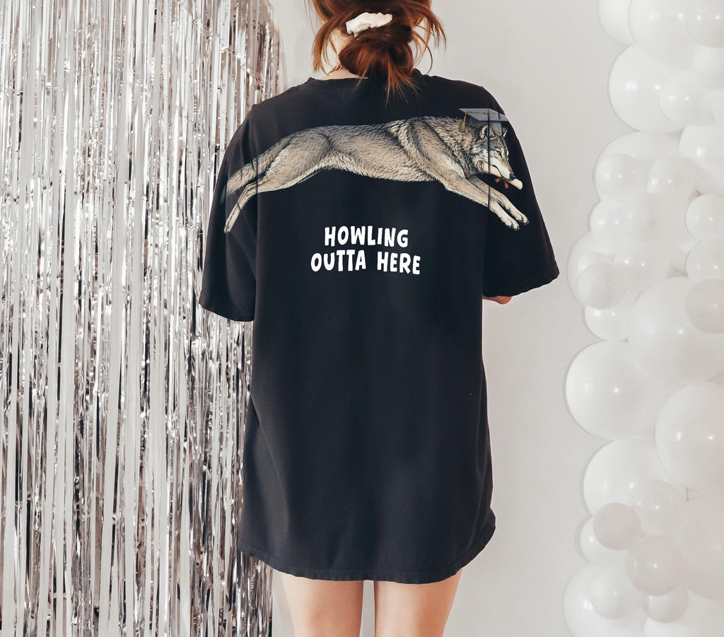 Wolf Howling Outta Here graduation graphic tee by Dripvity, unisex oversized white t-shirt with leaping wolf in graduation cap and diploma